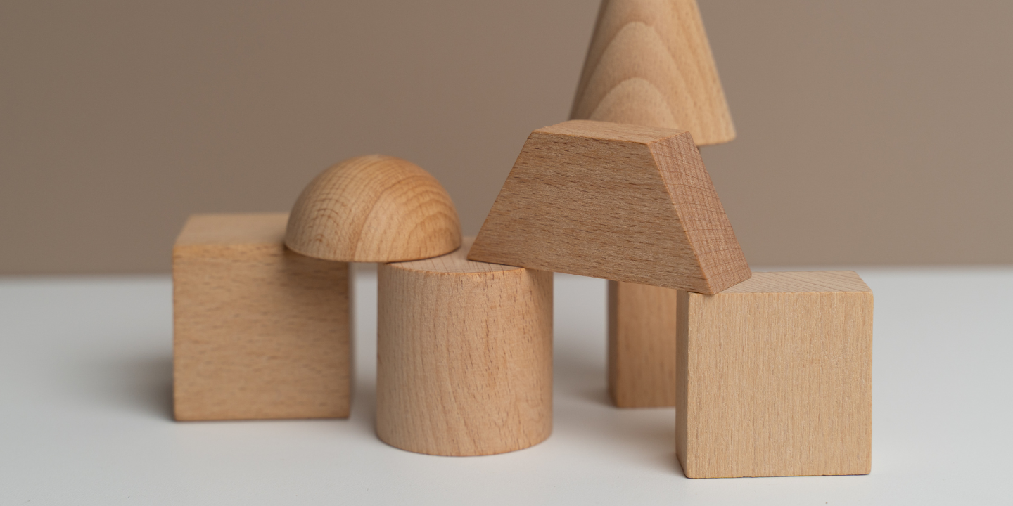 Assortment of wooden geometric shapes arranged on a table with a neutral-toned backdrop
