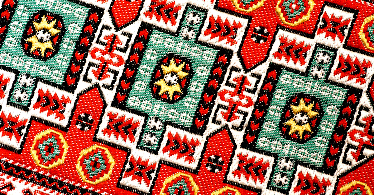 Colorful woven textile with a geometric star pattern in red, green, yellow, and white, showcasing detailed folk craftsmanship