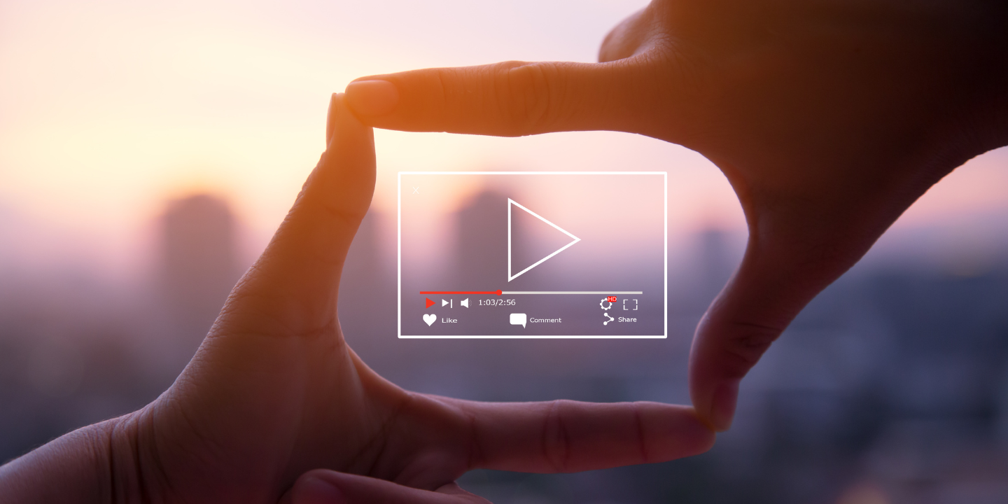 Hand framing a play button with social media icons against a sunset cityscape, symbolizing engaging video content marketing