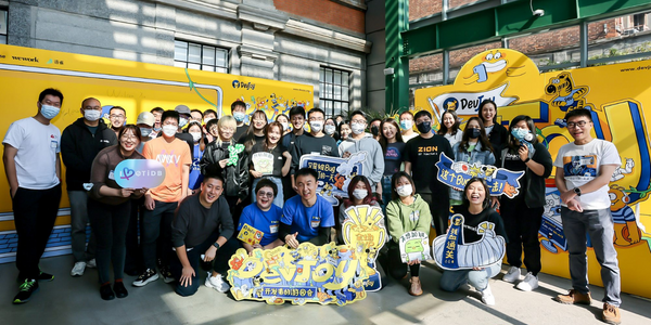 Group of masked individuals posing with signages at a festively adorned yellow public exhibit