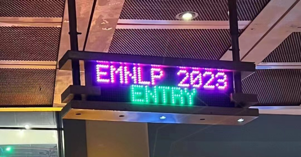 Illuminated sign reading "EMNLP 2023 Entry" mounted above a door, suggesting a conference entrance